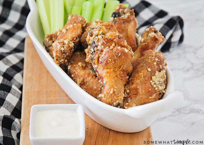 Baked Garlic Parmesan Chicken Wings in a bowl with celery and a small bowl of ranch dressing are a perfect super bowl appetizer