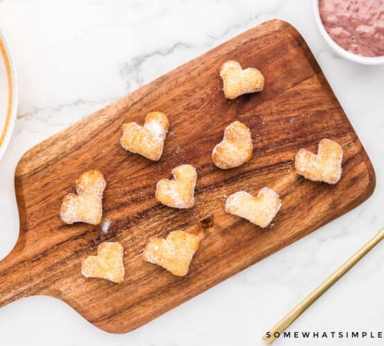 mini heart shaped donuts on a wood cutting board
