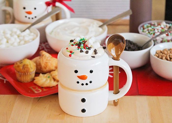 a hot cocoa bar with a snowman mug filled with hot chocolate