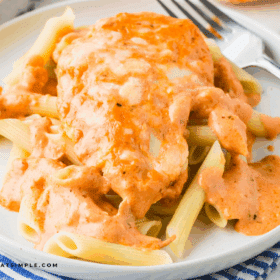 plated Cheesy Chicken Tomato Pasta with a fork and striped napkin