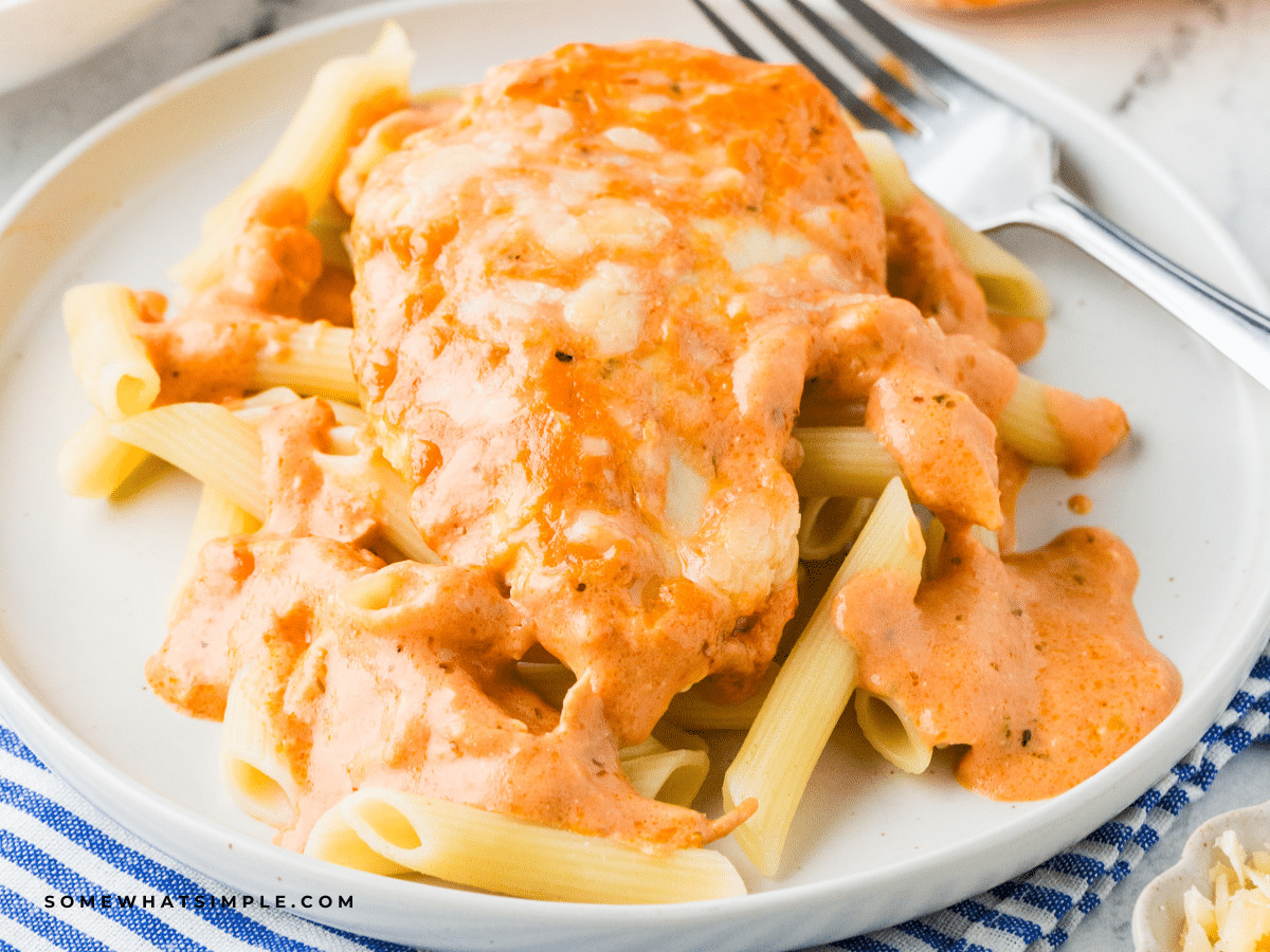 plated Cheesy Chicken Tomato Pasta with a fork and striped napkin