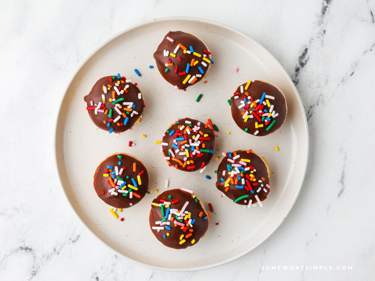 Chocolate Donut Muffins with rainbow sprinkles on a white plate
