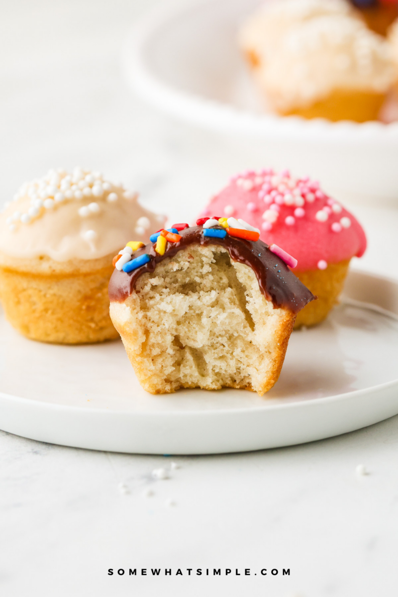 3 donut muffins on a white plate, one with a bite taken out of it.