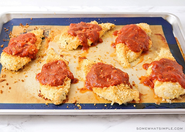 six baked chicken breasts with bread crumbs topped with marinara sauce that was put on the chicken after baking