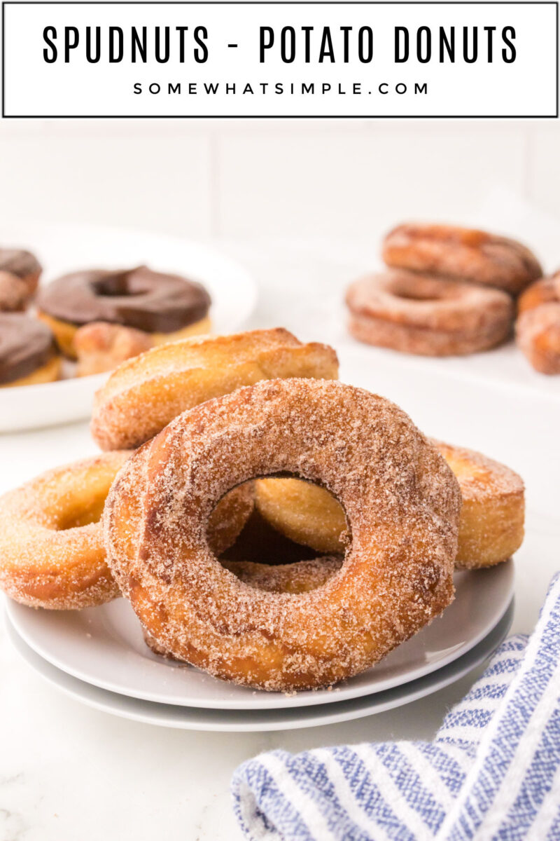 finished donuts on a stack of white plates