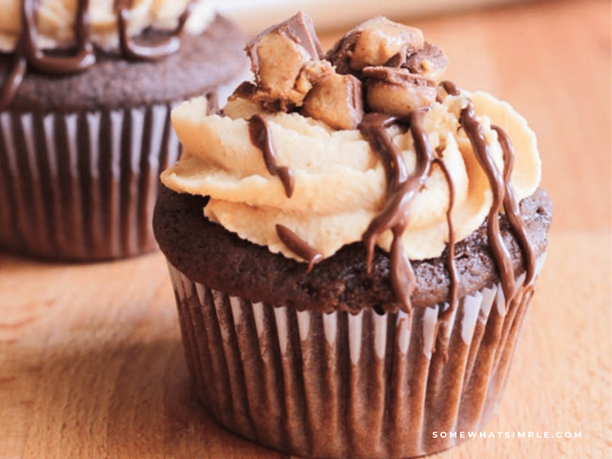 Chocolate Peanut Butter Cupcakes with a chocolate drizzle and Reese's candies on top.
