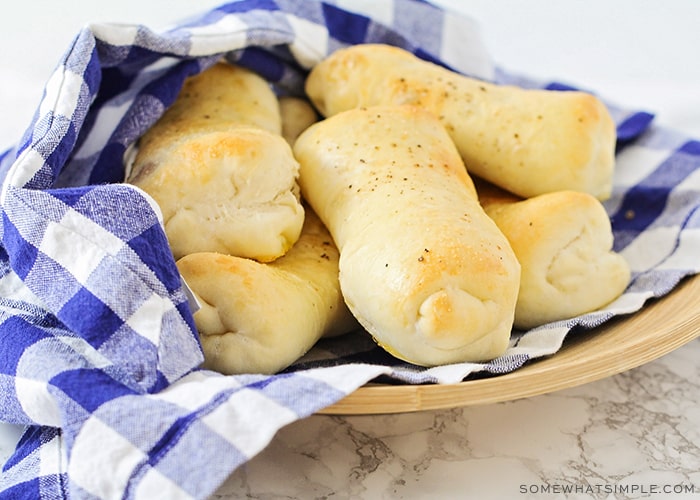 a bowl with six hot, golden brown, ham and cheese rolls fresh out of the oven.