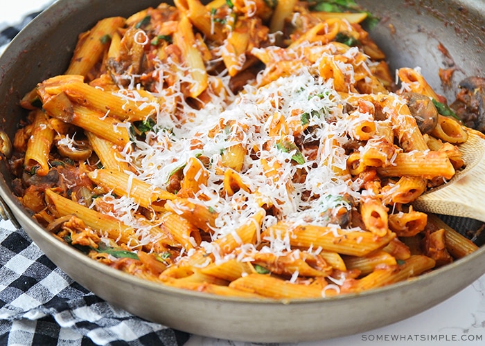 a large skillet filled with this chicken parmesan pasta recipe and topped with freshly grated parmesan cheese