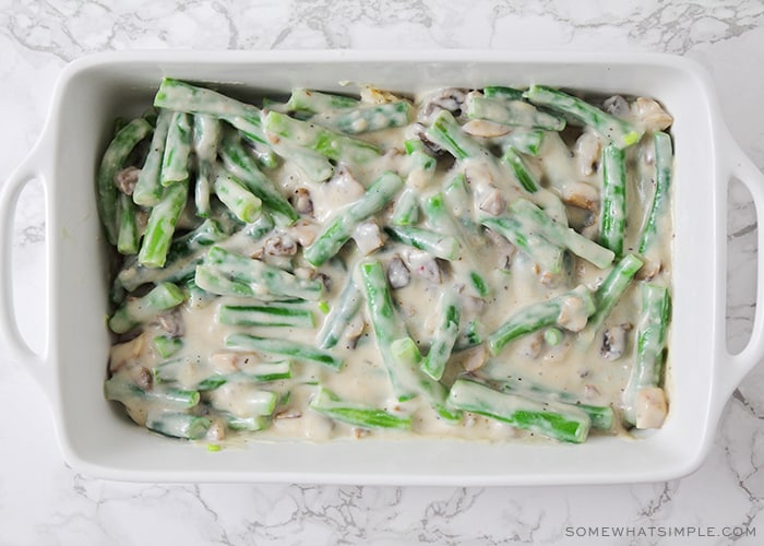 a white baking pan filled with fresh green beans and a creamy mushroom sauce