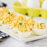 a long white serving tray filled with classic deviled eggs topped with paprika and parsley