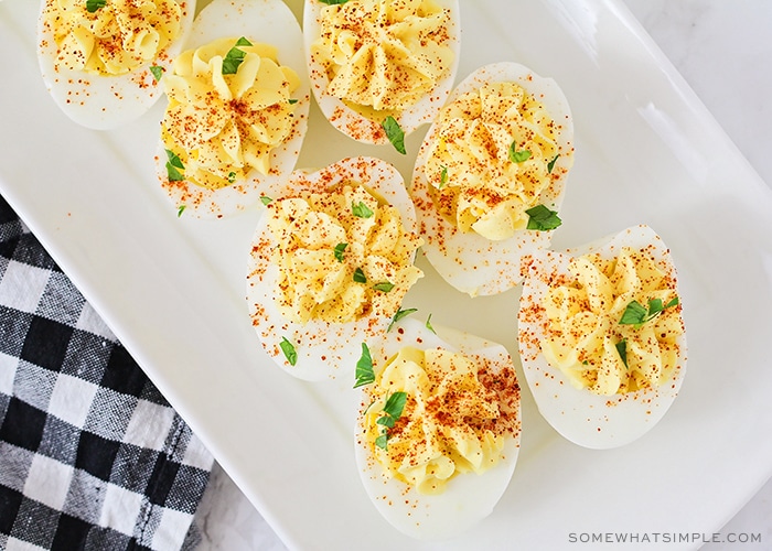 looking down on a white tray of the best deviled eggs topped with paprika and parsley that were made using this classic recipe