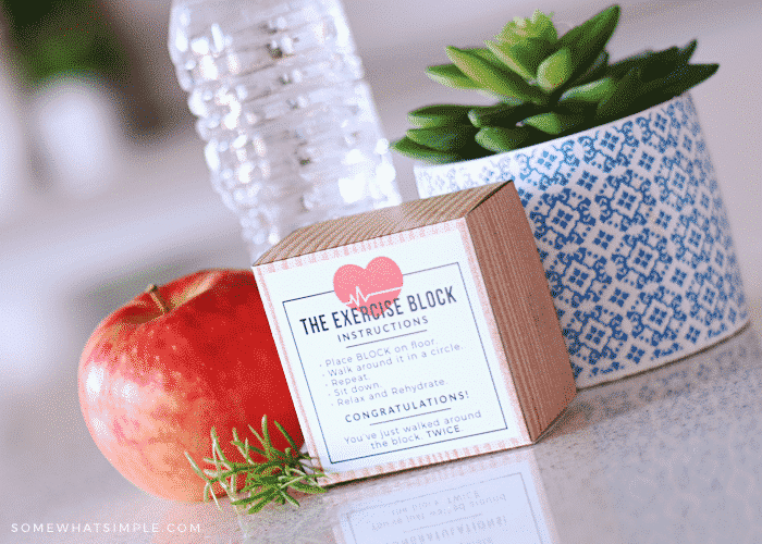 an exercise block with a funny printable on the outside sitting on a counter next to a bottle of water and an apple