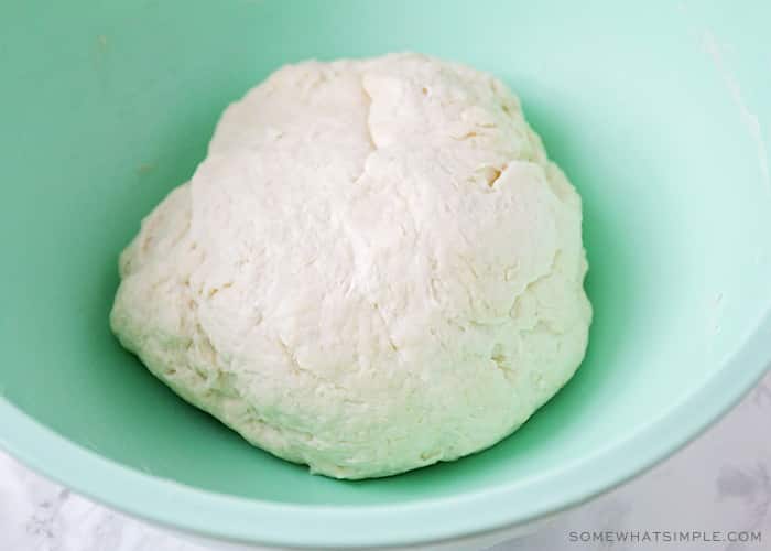 a large ball of tortilla dough in a light blue bowl