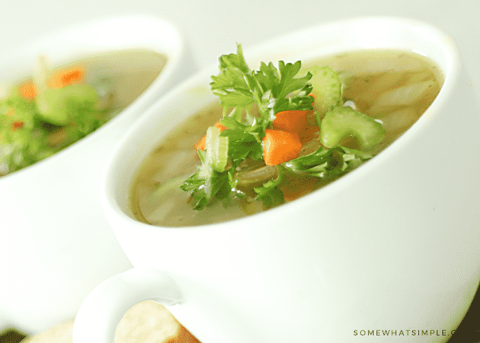 a cup filled with split pea and ham soup topped with chopped vegetables