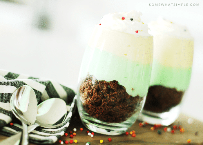 two pistachio parfait cups made with pistachio and vanilla pudding and brownie crumbles are a fun way to celebrate St Patrick's Day