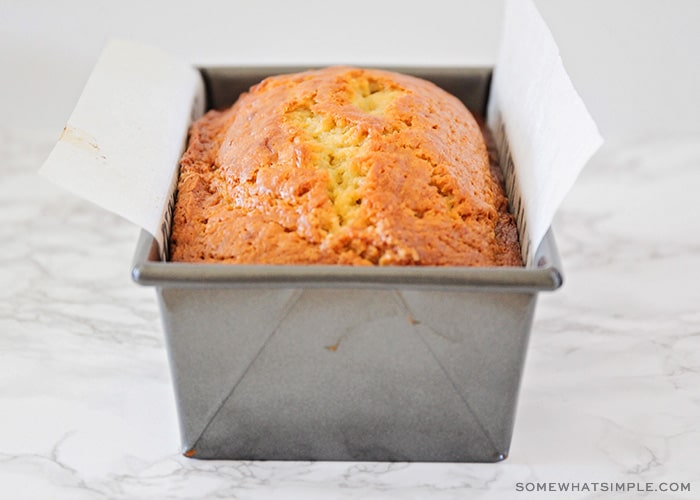 a metal pan with a baked loaf of banana bread made with sour cream that is golden brown on top