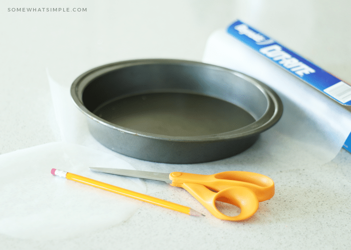 lining a round cake pan with parchment paper