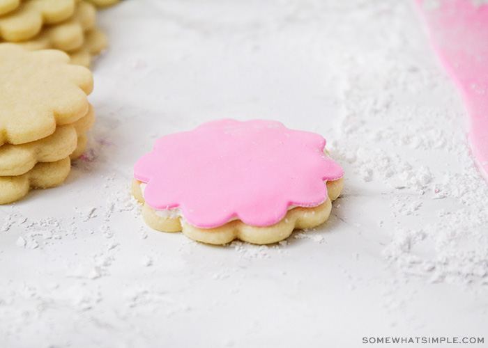 a sugar cookie in the shape of a flower is topped with pink homemade marshmallow fondant.