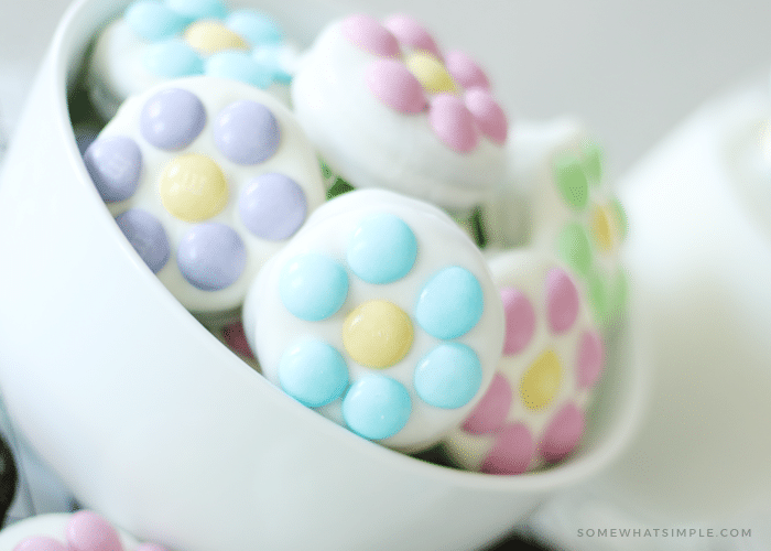 a close up picture of a white bowl filled with white chocolate covered Oreos with pastel colored m&ms