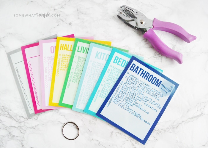 cleaning cards laid out on a white counter next to a hole punch