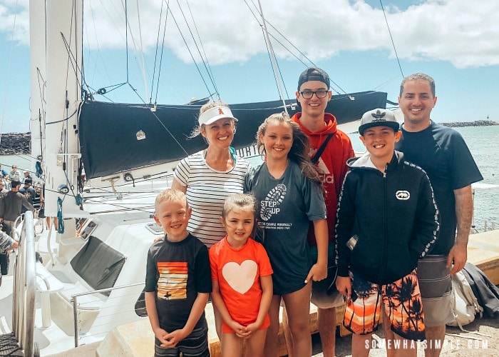 a good looking mom, her husband and five kids standing in front of a catamaran before sailing with Captain Andy's