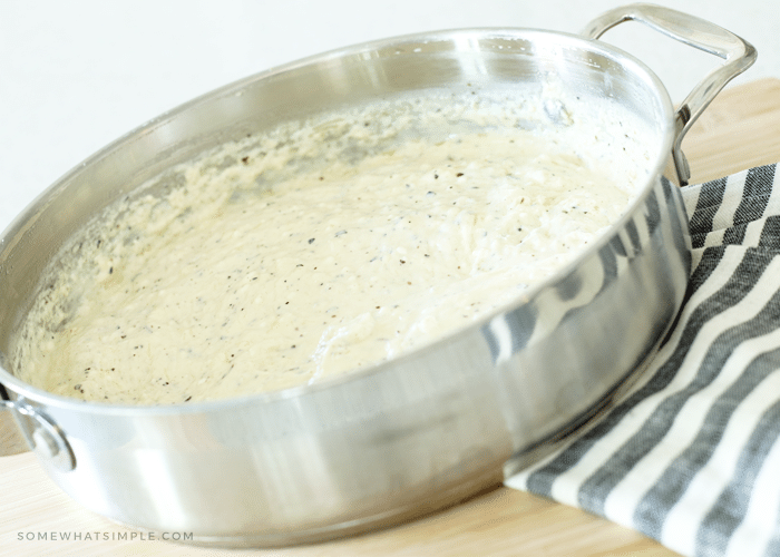 a large sauce pan filled with Alfredo sauce