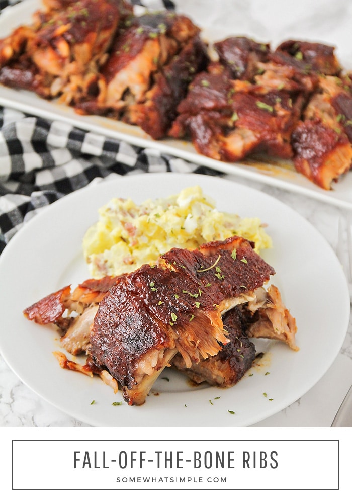 a white plate with three pork ribs and a side of potato salad. A tray of additional ribs hot off the grill are behind the plate. At the bottom of the picture the words fall off the bone ribs are written in black letters.