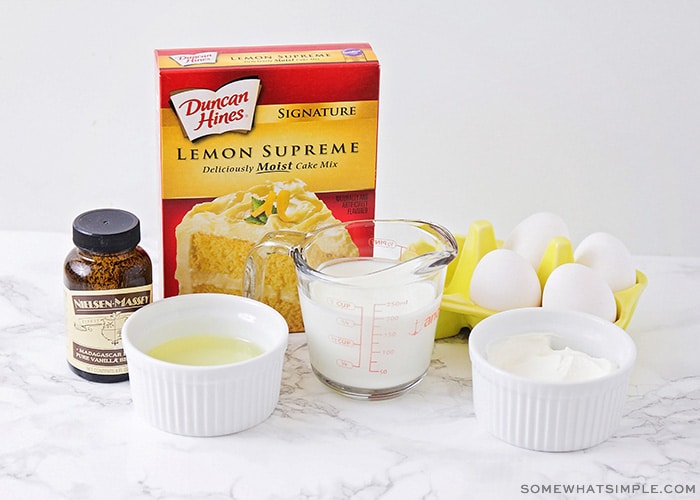 a box of lemon supreme duncan hines cake mix, a jar of vanilla, butter, milk, eggs and sugar sitting on a counter