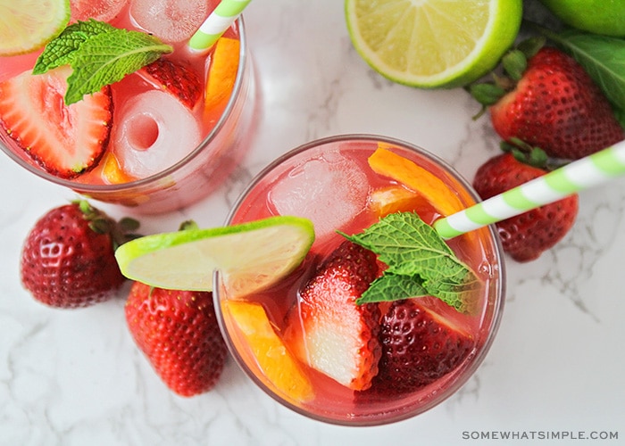 looking down on two glasses of alcohol free sangria with slices of fruit inside and a green striped straw in each glass.