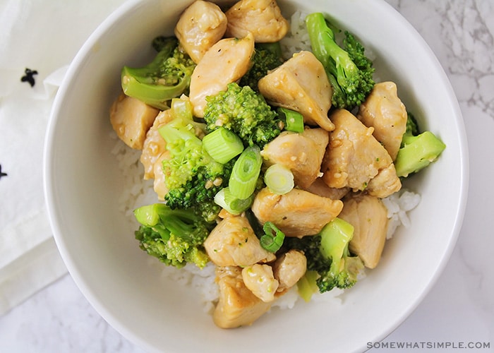 looking down on a bowl of broccoli stir fry with pieces of cooked chicken and rice