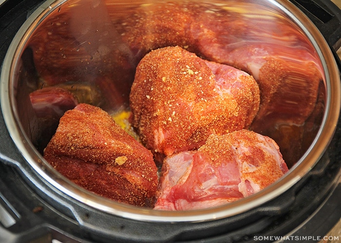 chunks of pork covered in a seasoned rub inside of an instant pot