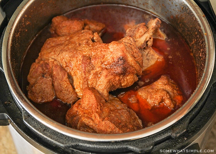 pieces of pork in a pressure cooker with the pieces partially submerged in a delicious sauce
