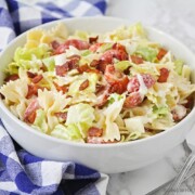 a white bowl of bow tie BLT pasta salad with lettuce, bacon and tomatoes.