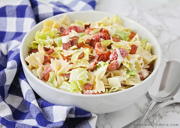 a white bowl of bow tie BLT pasta salad with lettuce, bacon and tomatoes.