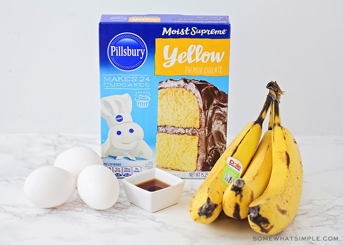 a box of yellow cake mix, 3 eggs, vanilla and a small bunch of bananas sitting on a counter