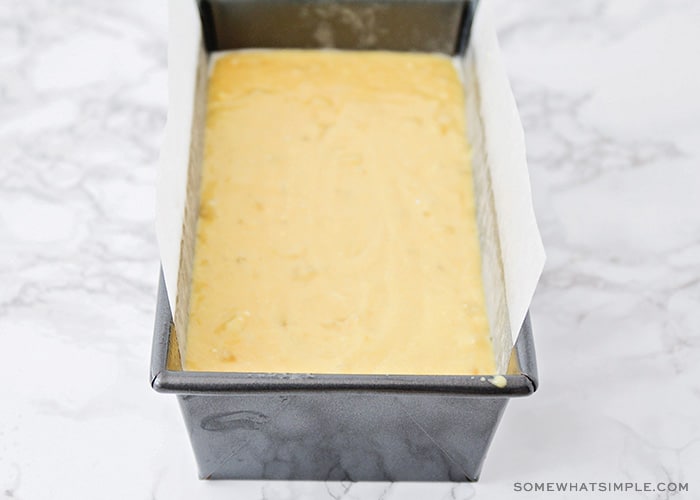 cake mix banana bread batter in a bread pan that is lined with parchment paper