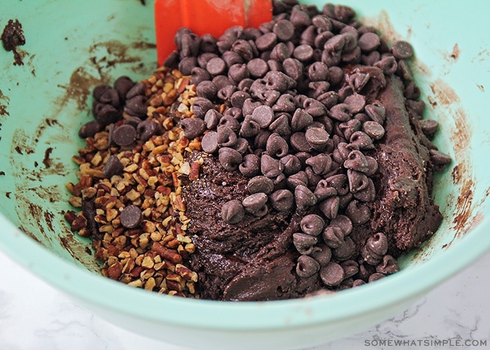 a mixing bowl filled with batter, chocolate chips and chopped nuts