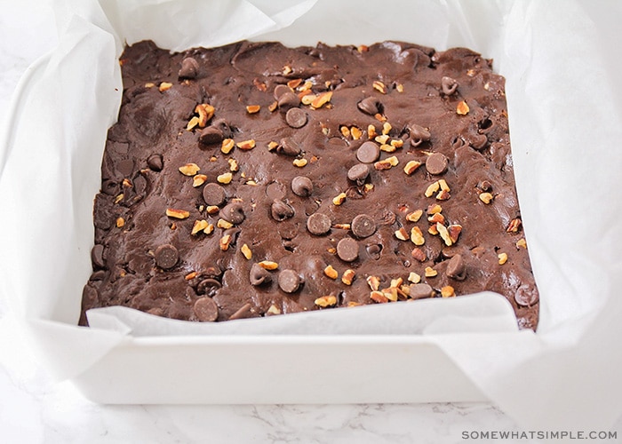 a square baking dish filled with cake mix batter topped with chocolate chips and chopped nuts