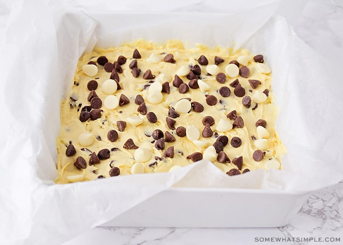 a square baking pan filled with cake mix dough and topped with chocolate chips