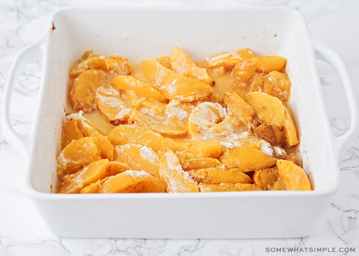 slices of peaches in a baking dish that have been tossed in flour