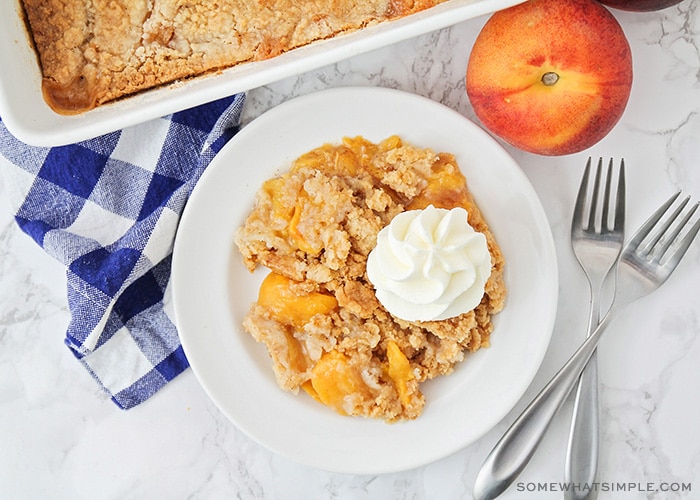 looking down on a serving of peach cobbler, made with cake mix, topped with whipped cream