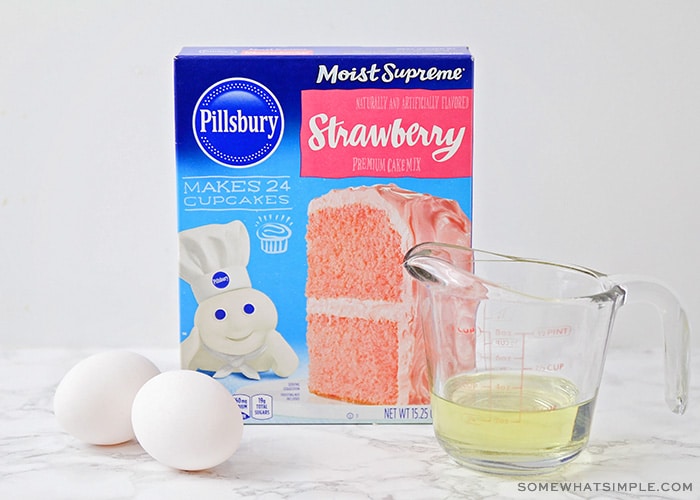 a box of Pillsbury strawberry cake mix, two eggs and oil sitting on a counter