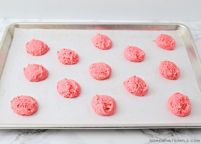 a cookie sheet lined with parchment paper with cake batter balls spread over the sheet