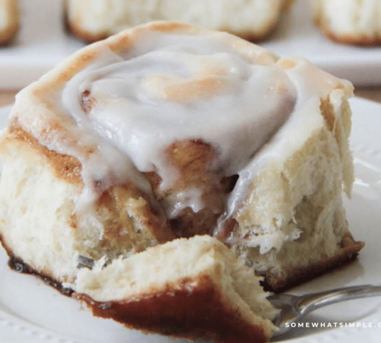 brown sugar cinnamon roll, plated and being cut into with a fork