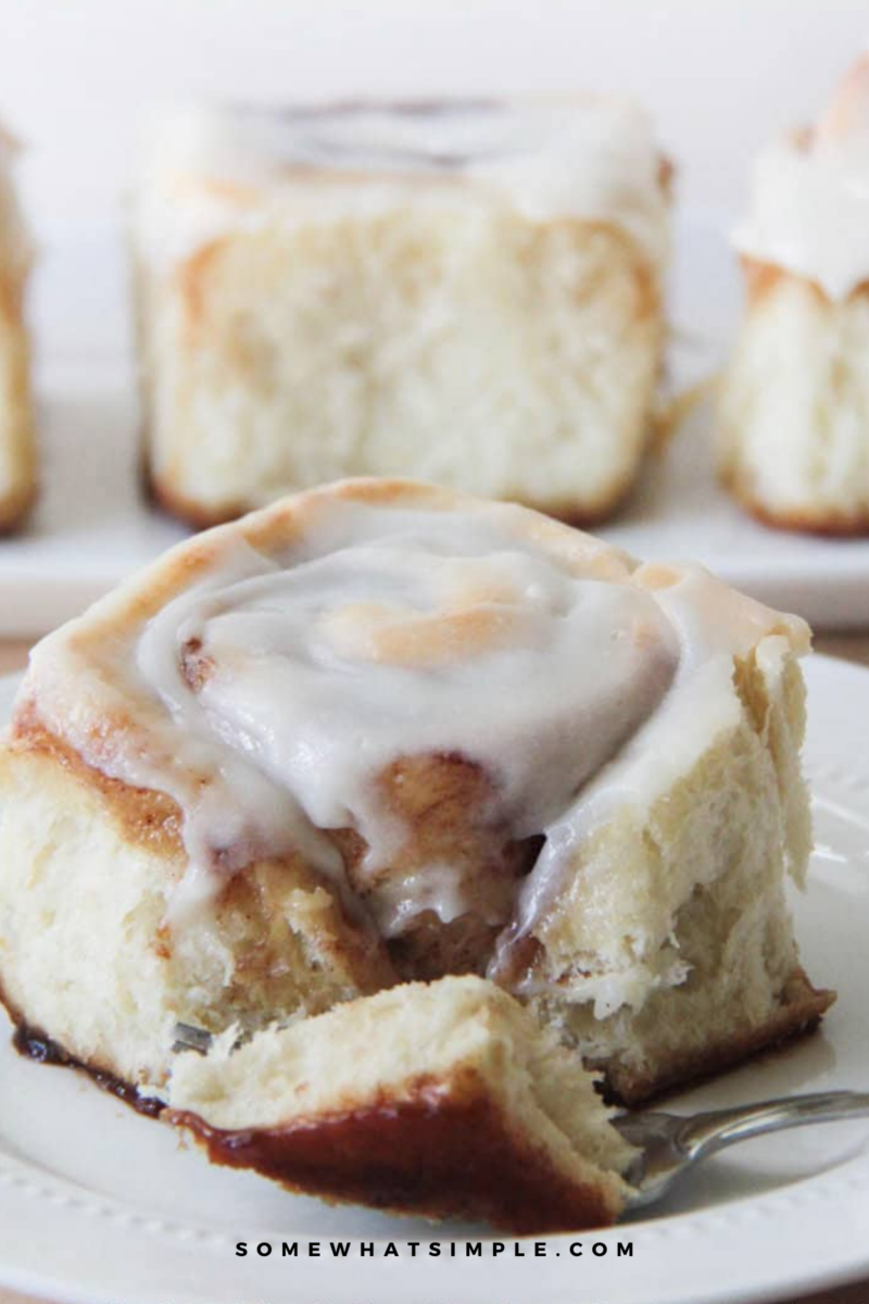 long image closeup of a brown sugar cinnamon roll with more rolls in the background