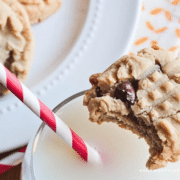 PB Choc Chip Cookie on the edge of a glass of milk