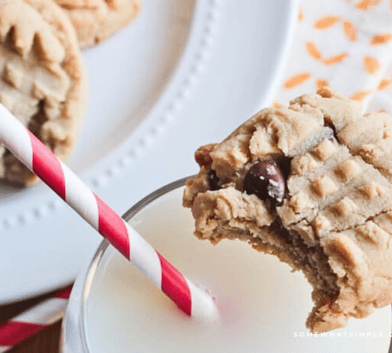 PB Choc Chip Cookie on the edge of a glass of milk