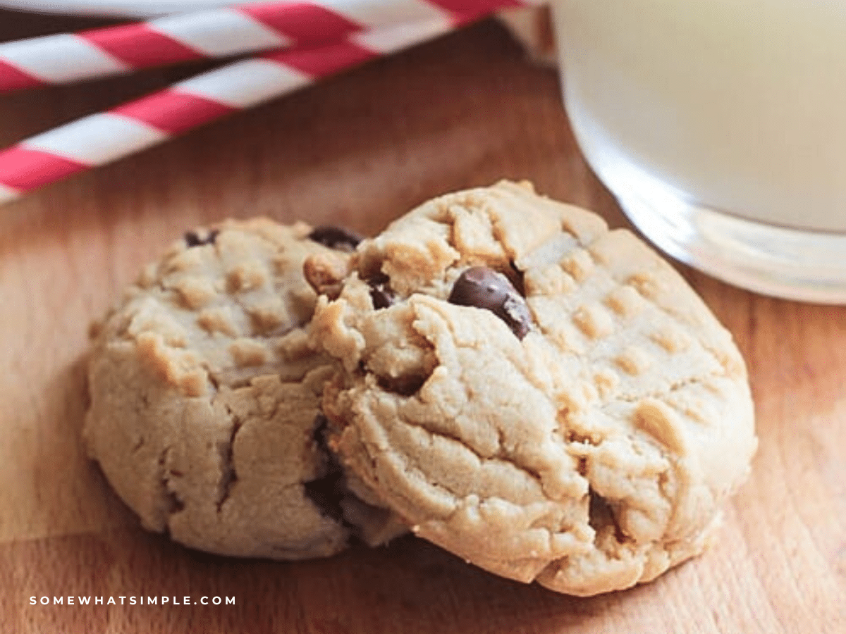 two PB Choc Chip Cookies with a glass of milk in the background