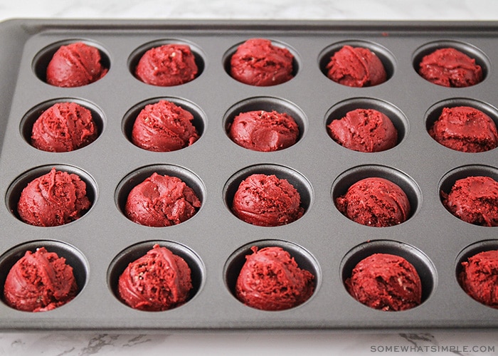 a mini muffin tin that has red velvet cake batter in each of the holes