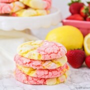 a stack of strawberry lemonade cookies on a counter next to strawberries and lemons